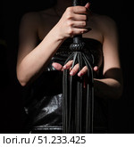 BDSM concept. A woman in a leather corset holds a black lash with a long fringe. Role-playing games for adults. Close-up of sex toys for domination. The whip in female hands. Стоковое фото, фотограф Михаил Решетников / Фотобанк Лори