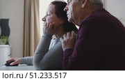 Senior couple using laptop together in the room. Embracing elderly man and woman reading email or online shopping choice. Old man and woman talk at table in home together on internet, social media. 4K. Стоковое видео, видеограф Марина Демидюк / Фотобанк Лори