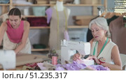 Elderly woman sewing female assistant drawing pattern on paper. Стоковое видео, видеограф Яков Филимонов / Фотобанк Лори