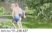 Children joyfully playing in a sprinkler on a warm and sunny summer day outside. Стоковое видео, видеограф Olesia Kondrateva / Фотобанк Лори