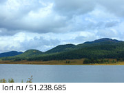 A Serene Lake Nestled Within the Embrace of Lush Green Mountains. Стоковое фото, фотограф Igor Bastrakov / Фотобанк Лори