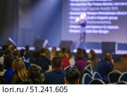 Conference speaker addressing audience on stage with large screen in background. Стоковое фото, фотограф Антон Гвоздиков / Фотобанк Лори