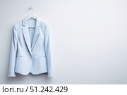 Women's business blazer without human model. Female office classic light blue jacket, coat for ladies with button, long sleeves hanging on a hanger on white background. Mock up, template. Suit jacket. Стоковое AI-изображение, AI-художник Марина Демидюк / Фотобанк Лори