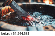 Forging a sword in molten metal at a traditional workshop during the late afternoon. Стоковое AI-изображение, AI-художник Александр Довянский / Фотобанк Лори