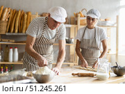 Baker uses knife to cut pieces of raw dough to make croissants. Стоковое фото, фотограф Татьяна Яцевич / Фотобанк Лори