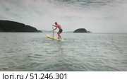 Athletic man practicing turns, loses balance and falls from paddle board into sea during summer fun. Action moment full of energy and laughter on warm vacation day with ocean adventure vibes. Стоковое видео, видеограф Енваев Андрей / Фотобанк Лори