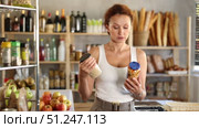 Female shopper carefully choosing jar of canned beans in a grocery supermarket. Стоковое видео, видеограф Яков Филимонов / Фотобанк Лори