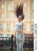 portrait of a girl in jeans and a t-shirt on the background of the building in the evening on a summer day. street dancing in the city. Стоковое фото, фотограф Арзюков Вадим Николаевич / Фотобанк Лори
