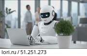 Futuristic humanoid robot with glowing blue eyes is working on a laptop in a modern office environment, showcasing advanced technology and innovation in the workplace. Стоковое AI-видео, аниматор Ирина Ручушкина / Фотобанк Лори
