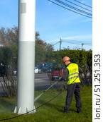 A man in a yellow vest is cleaning a pole with a hose. Russia. Moscow. 05.09.25. Редакционное фото, фотограф Ярославский Максим / Фотобанк Лори