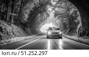 Black And White Photo Of A Car Speeding Through A Winding Forest Road. Generative AI. Стоковое AI-изображение, AI-художник Roman Zavorotny / Фотобанк Лори