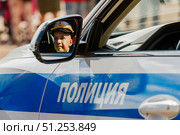 Боковое зеркало полицейского автомобиля с надписью "Полиция" отражает лицо улыбающегося мальчика в фуражке. Редакционное фото, фотограф Кирилл Сиротюк / Фотобанк Лори