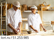 Elderly male chef and female skillfully kneads dough to bake delicious bread and croissants. Стоковое фото, фотограф Татьяна Яцевич / Фотобанк Лори