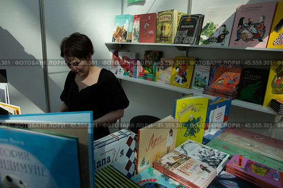 06.04.2023, Москва. Международная ярмарка интеллектуальной литературы «non/fictioNвесна» в Гостином дворе. Девушка среди книг на прилавке. Редакционное фото, фотограф Дмитрий Киселёв / Фотобанк Лори
