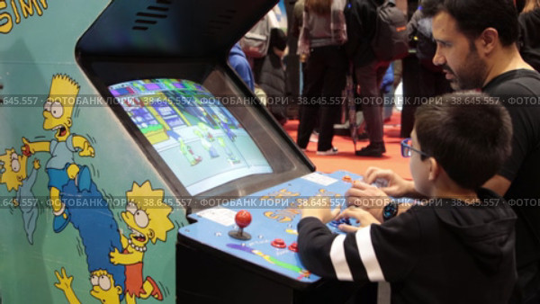 11-17-2022 LISBON, PORTUGAL - a boy playing The Simpsons arcade game at the gaming expo. Редакционное видео, видеограф Константин Шишкин / Фотобанк Лори