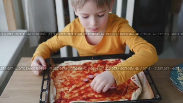 6 years old boy cooking pizza in the kitchen. Child rolling up the dough, adding cheese, tomatoes and smear sauce the base. Preschool kid making homemade pizza. Cooking class, culinary. Little baker. Стоковое видео, видеограф Марина Демидюк / Фотобанк Лори