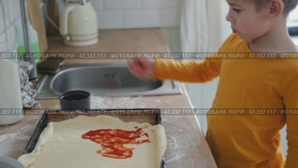 6 years old boy cooking pizza in the kitchen. Child rolling up the dough, adding cheese, tomatoes and smear sauce the base. Preschool kid making homemade pizza. Cooking class, culinary. Little baker. Стоковое видео, видеограф Марина Демидюк / Фотобанк Лори