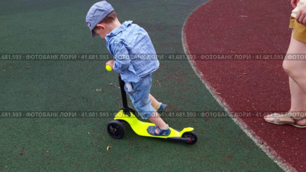 A baby learns to ride a children scooter. A mother woman teaches a child to ride a scooter. Kid boy aged two years (two-year-old) Стоковое видео, видеограф Андрей Журавлев / Фотобанк Лори