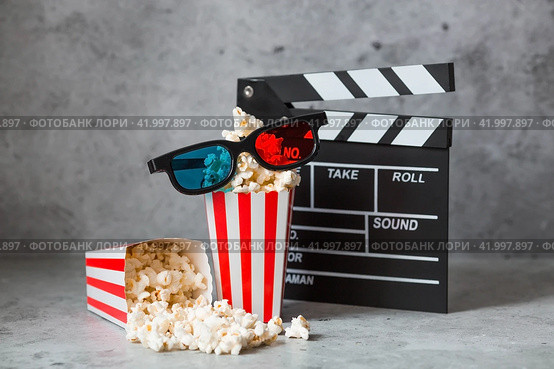 A banner for the film industry. A movie date. A movie camera, 3D glasses, popcorn in striped cups on a stylish concrete gray background. The premiere of the film. (2024 год). Стоковое фото, фотограф Photojuli / Фотобанк Лори