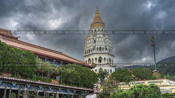 A beautiful ancient seven-tiered pagoda Ban Po Thar against a cloudy sky. Monastery houses among the green vegetation in the foreground. Malaysia. Penang. Kek Lok Si Temple (2023 год). Стоковое фото, фотограф Вера Ивановна Кубарева / Фотобанк Лори