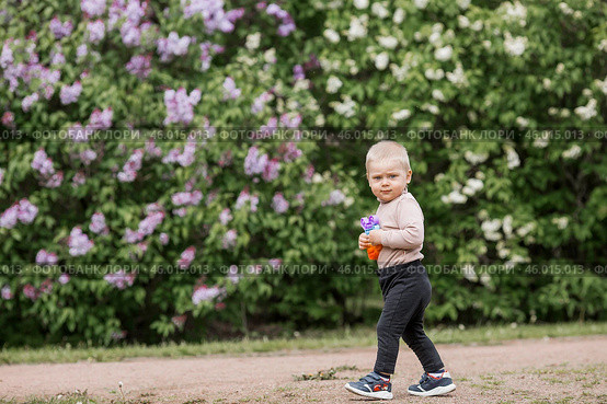 A beautiful chubby 2-year-old child in the park with a colorful Pop-it game. An anti-stress remedy. A pop It toy in children's hands. Стоковое фото, фотограф Photojuli / Фотобанк Лори