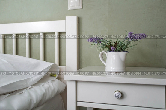 A bed with white sheets and a vintage Provence-style bedside table in a hotel room or a home bedroom. Space for the text. Enjoying the morning concept. Стоковое фото, фотограф Photojuli / Фотобанк Лори