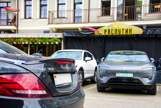 A black car is parked next to a white car near the Rasputin restaurant. Belarus. Minsk. 05.08.25. Редакционное фото, фотограф Ярославский Максим / Фотобанк Лори