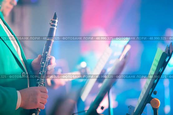 A blurred musical background in which hands hold a saxaphone in front of a staff. Musical poster or advertisement for a brass concert. Стоковое фото, фотограф Лазаренко Светлана / Фотобанк Лори