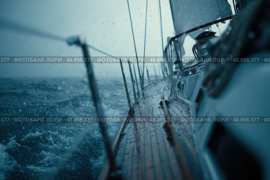A boat is sailing in the ocean with rain pouring down on it. Стоковое AI-изображение, AI-художник Ярославский Максим / Фотобанк Лори
