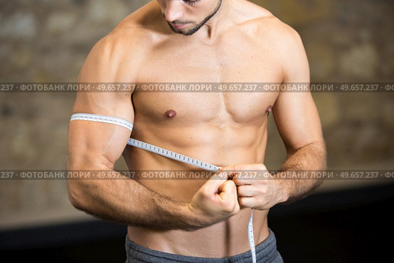 a bodybuilder measuring his biceps. Стоковое фото, агентство Ingram Publishing / Фотобанк Лори