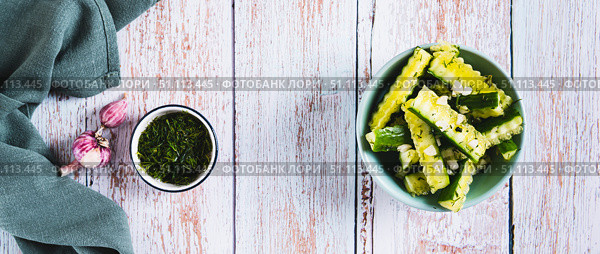 A bowl of spicy lightly salted cucumbers with herbs on the table top view web banner. Стоковое фото, фотограф Елена Руй / Фотобанк Лори