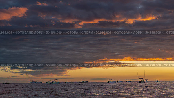A bright sunset over the ocean. Purple clouds are highlighted in scarlet. The sky is orange on the horizon. Silhouettes of boats in the sea. Madagascar. Nosy Be. Стоковое фото, фотограф Вера Ивановна Кубарева / Фотобанк Лори