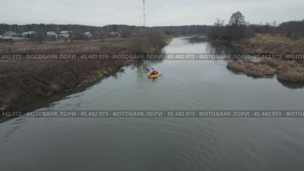 A bright yellow kayak with two rowers slowly sails along the quiet autumn cold river. They row slowly and confidently with oars, guiding the boat along the riverbed. Aerial photography from a drone. Стоковое видео, видеограф Ярославский Максим / Фотобанк Лори