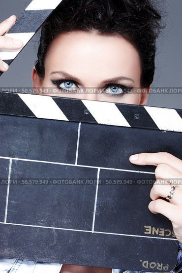A brunette woman with a blue eyes looking through a clapperboard.. Brunette woman with blue eyes looking through a clapperboard. Стоковое фото, агентство Ingram Publishing / Фотобанк Лори