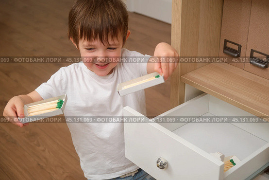 A child boy is holding a lit matchstick, which is highly flammable and risky. The baby is dangerously playing with a flame inside the house. Kid aged 3 years (three year old boy) Стоковое фото, фотограф Андрей Журавлев / Фотобанк Лори
