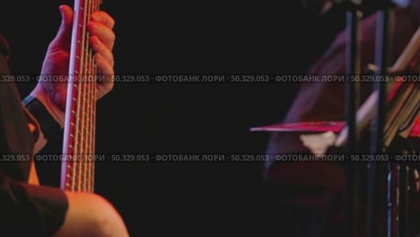 A close-up of a musician's hand deftly clasping the strings on a bass guitar fingerboard, illuminated by a bright stage light against a dark background. Стоковое видео, видеограф Воловодов Владимир / Фотобанк Лори