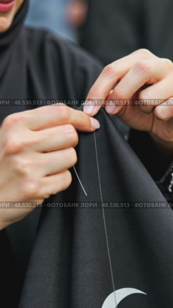 A close-up of a woman's hands sewing a black cloth banner, her fingers trembling slightly as she prepares for the Ashura process. Стоковое AI-видео, аниматор Sergey Grishin / Фотобанк Лори