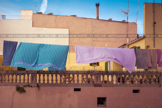 A colorful clothesline in front of an old house and a blue sky in Spain. Стоковое фото, фотограф Rüdiger Wittmann / Smarterpix / Фотобанк Лори