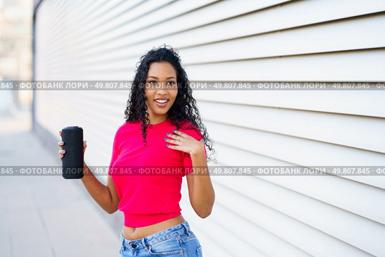 A confident woman wearing a vibrant pink crop top and stylish denim shorts poses joyfully with a refreshing drink in hand, radiating positivity and cheer against a modern and fashionable backdrop. A Confident Woman Posing with a Drink in Hand Against a Stylish Modern Background Setting. Стоковое фото, агентство Ingram Publishing / Фотобанк Лори