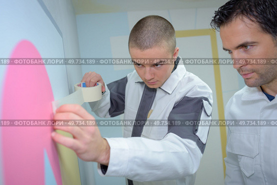 a decorator applying masking tape. Стоковое фото, агентство Ingram Publishing / Фотобанк Лори