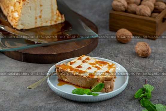 A delectable slice of molotof, a traditional caramelized egg white pudding drizzled with sweet syrup and garnished with fresh mint leaves, sits on a light blue plate. Стоковое фото, агентство Ingram Publishing / Фотобанк Лори