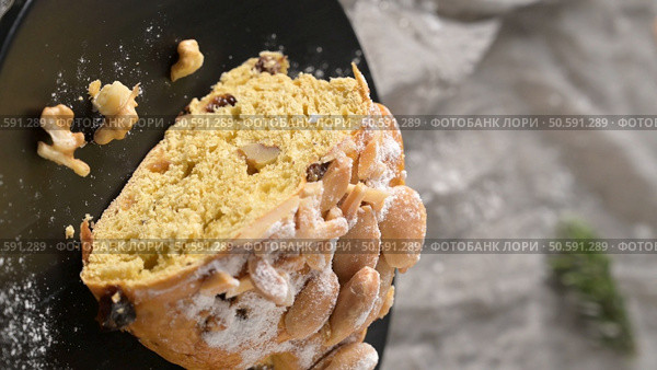 A delicious slice of Bolo Rainha cake with nuts raisins and powdered sugar on a black plate a festive treat perfect for sharing and enjoying during special occasions. Стоковое фото, агентство Ingram Publishing / Фотобанк Лори