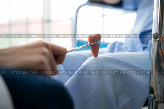 A doctor uses a reflex hammer to evaluate a patient’s knee joint. Стоковое фото, агентство Ingram Publishing / Фотобанк Лори