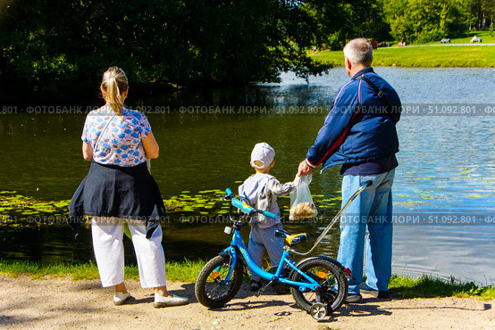 A family of three is standing by a body of water. Russia. Moscow. 17.08.25. Редакционное фото, фотограф Ярославский Максим / Фотобанк Лори