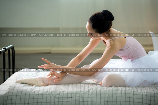 A girl ballet student, Warm up in bed in bedroom before practicing ballet at home. Стоковое фото, агентство Ingram Publishing / Фотобанк Лори