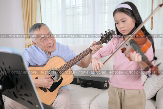 A girl violinist and her grandfather practice music together at home. Стоковое фото, агентство Ingram Publishing / Фотобанк Лори