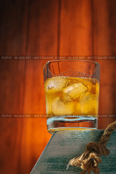 A glass of whiskey with ice on a stand. Wooden background. Alcoholic drink. Moscow Russia March 27, 2022. Стоковое фото, фотограф Юрий Поздников / Фотобанк Лори