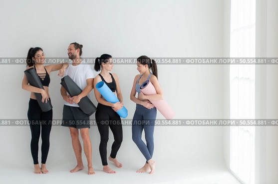 A group of female and male athletes stood and chatted amicably in the studio before beginning with the yoga class. Стоковое фото, агентство Ingram Publishing / Фотобанк Лори