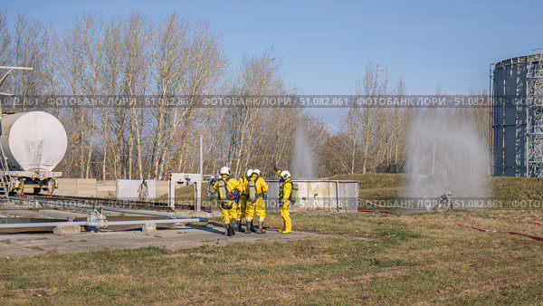 A group of rescuers equipped with breathing apparatus at the scene of an accident at a petrochemical plant. Elimination of an accident at a petrochemical plant. There is an emergency at the factory. Стоковое фото, фотограф Эдуард Белкин / Фотобанк Лори