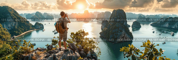 A hiker enjoys the breathtaking sunset over Ha Long Bay while capturing the stunning landscape with a camera. Стоковое AI-изображение, AI-художник Данила Большаков / Фотобанк Лори